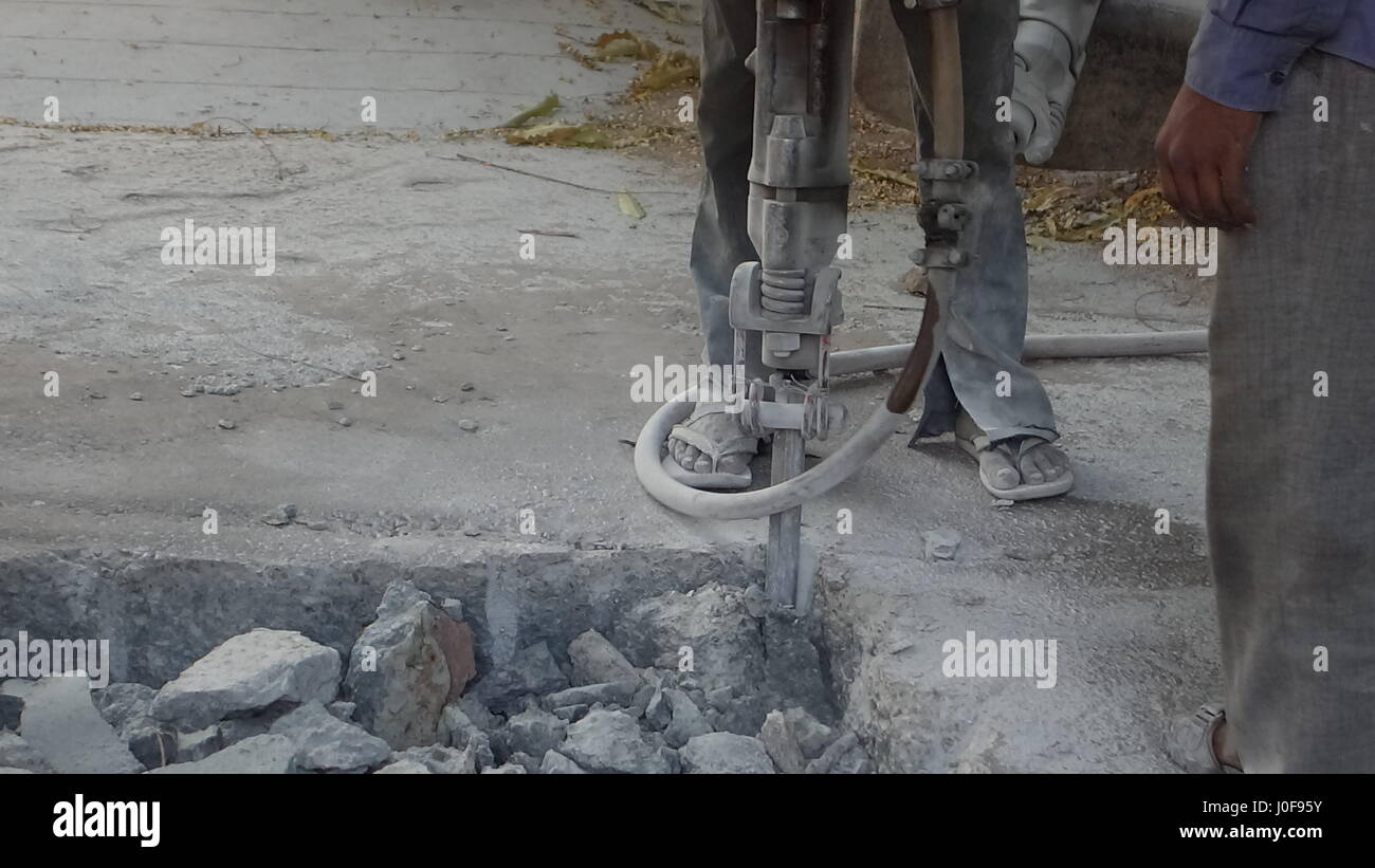 Indian operai usando il martello pneumatico per perforare un marciapiede della città Foto Stock
