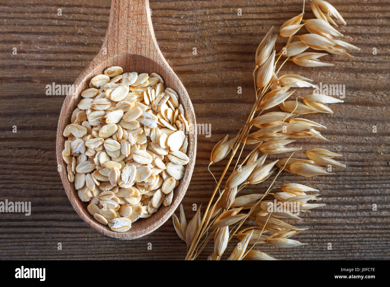 Farina di avena sul cucchiaio di legno. Tavolo in legno come sfondo Foto Stock