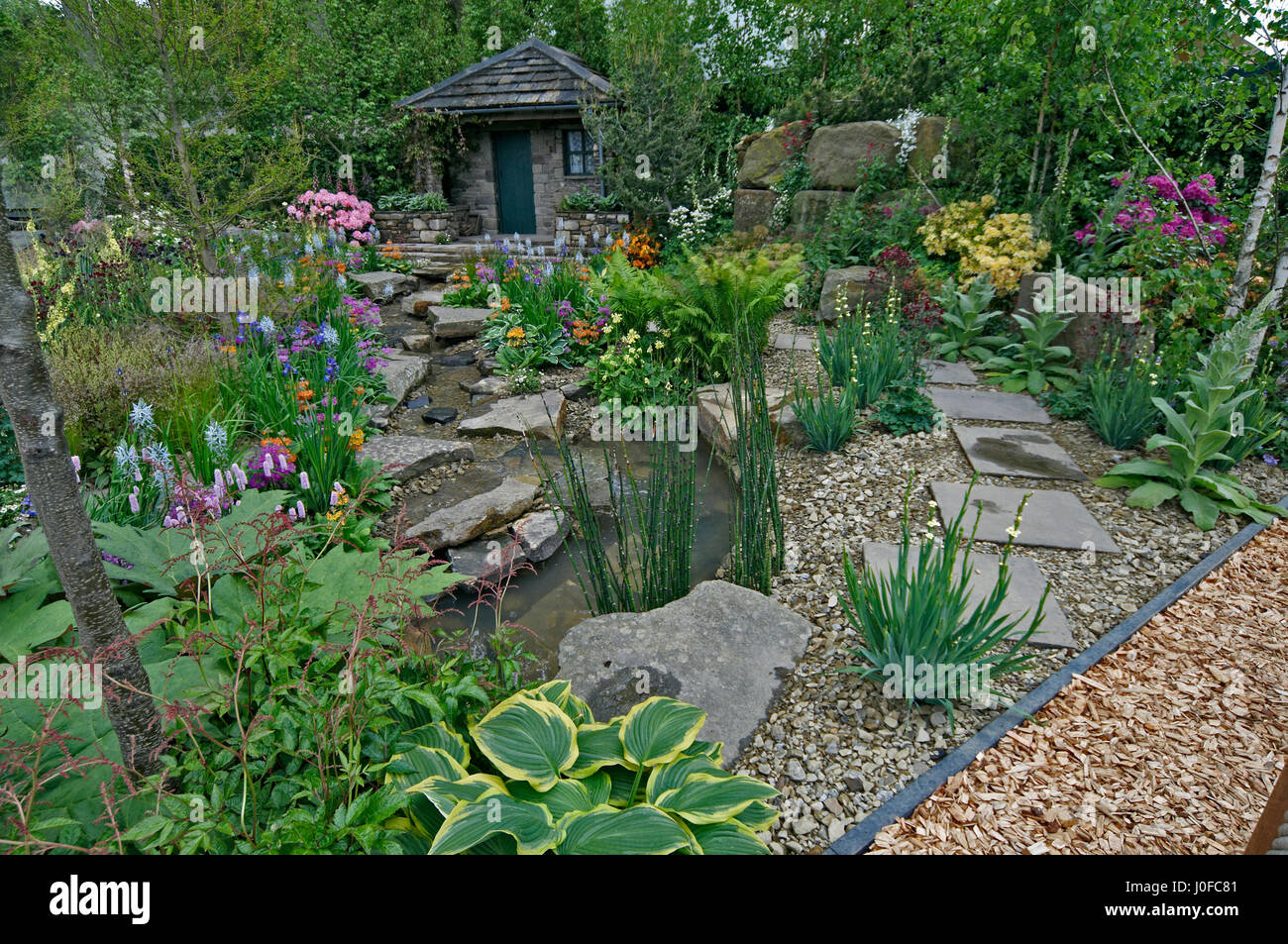 Un paese Garden cottage in una boscosa rockery con colorati piantagione Foto Stock