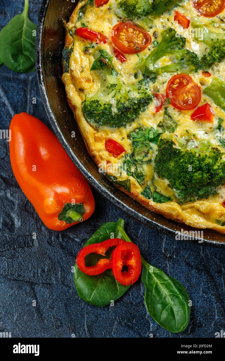 Frittata con i broccoli, spinaci, peperoni e pomodori in padella di ferro.  Tipo di italiano frittata con verdure Foto stock - Alamy