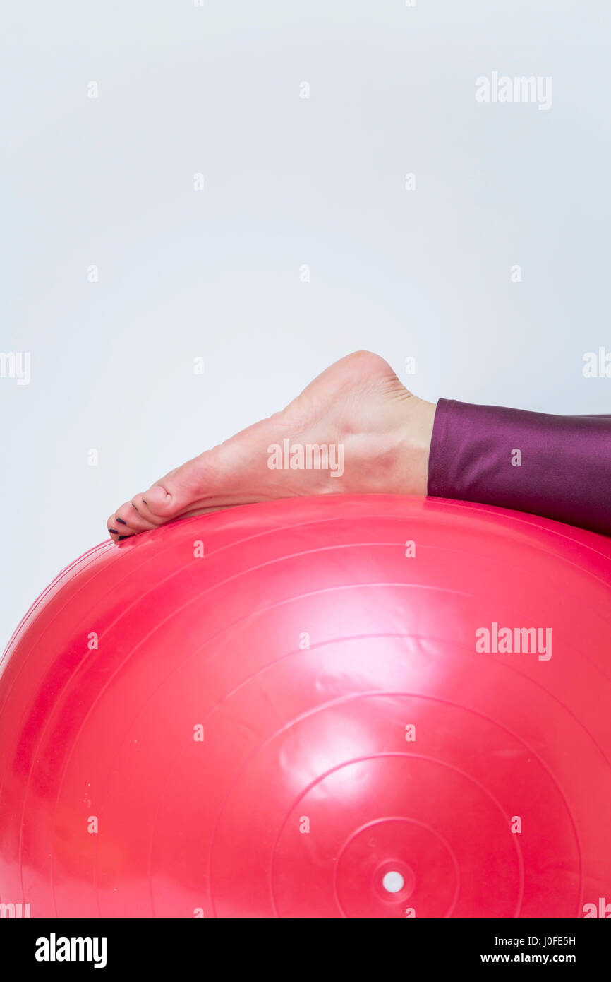 Giovane donna esercizio con red pilates ball isolato su bianco Foto Stock