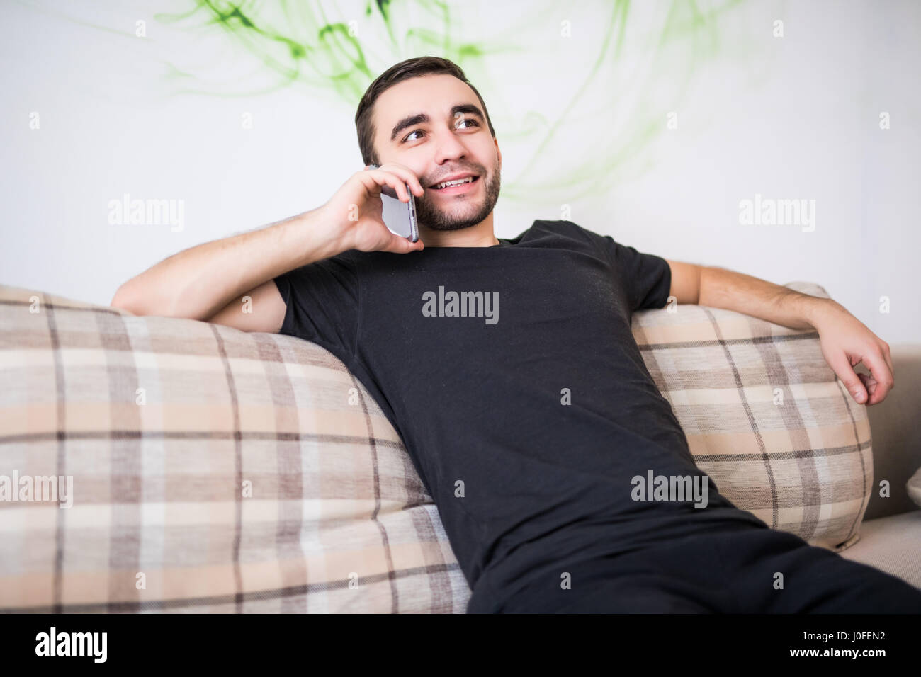 Giovane uomo sul cellulare in salotto Foto Stock