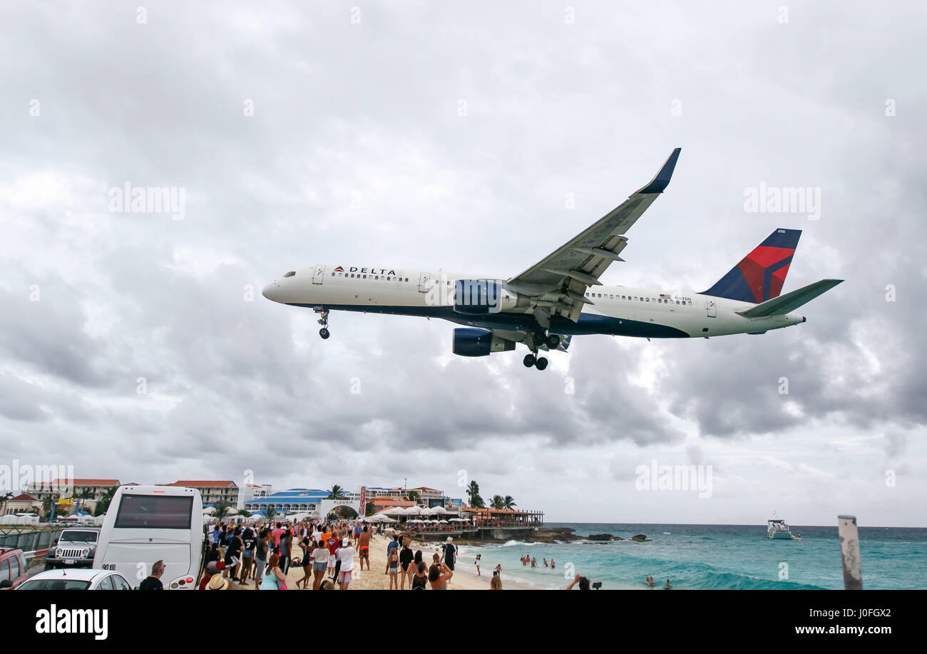 Un Delta jet del passeggero è in atterraggio a la principessa Juliana aeroporto sorvolando una spiaggia popolare con i turisti. Foto Stock