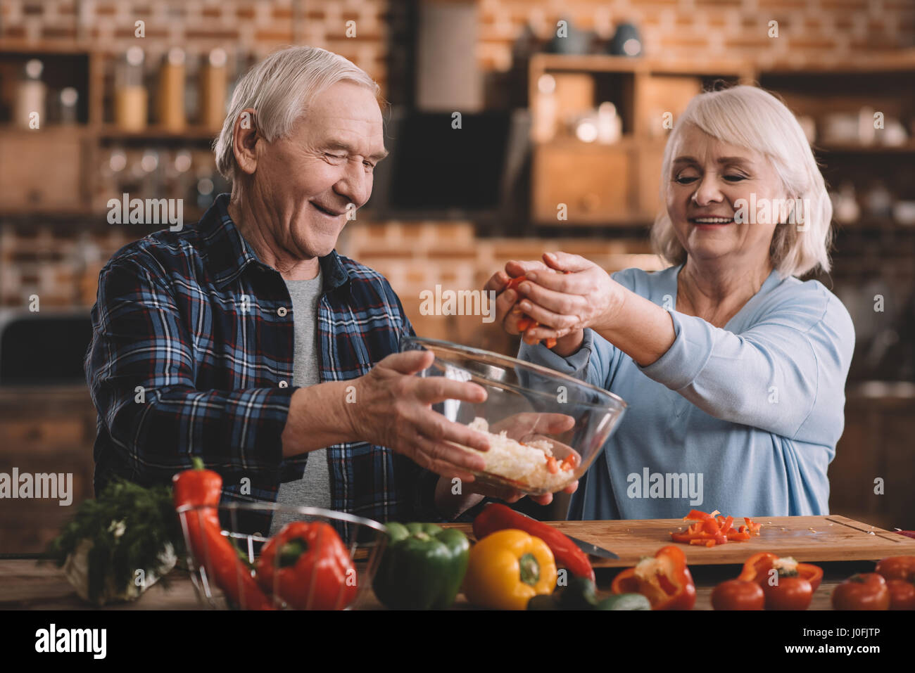 Ritratto di sorridente coppia senior insalata di rendere insieme in cucina Foto Stock