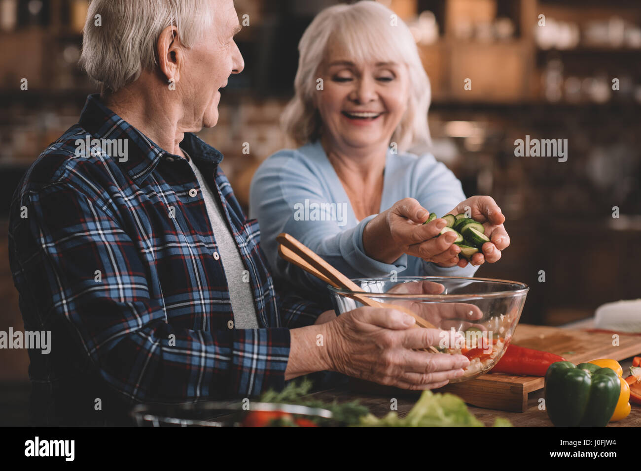 Ritratto di donna senior mettendo i cetrioli in un recipiente in marito le mani Foto Stock