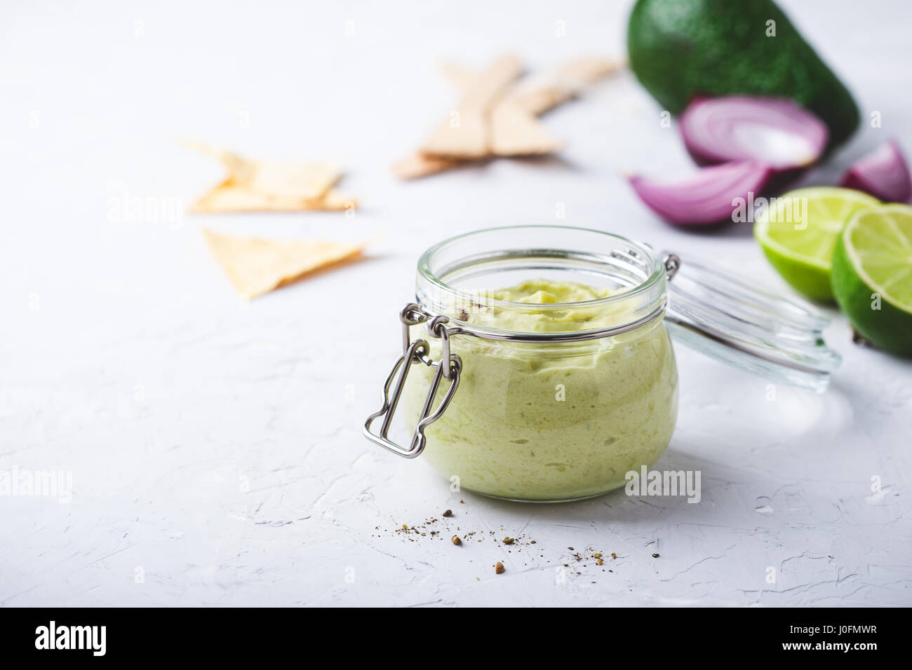 In casa cremosa salsa di avocado con lo yogurt greco in barattolo, Delizioso condimento per insalata su grigio chiaro sfondo intonacato Foto Stock