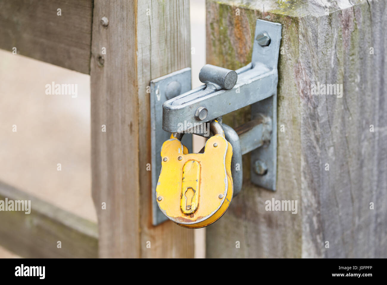Lucchetto giallo su un chiuso i cancelli privato Foto Stock