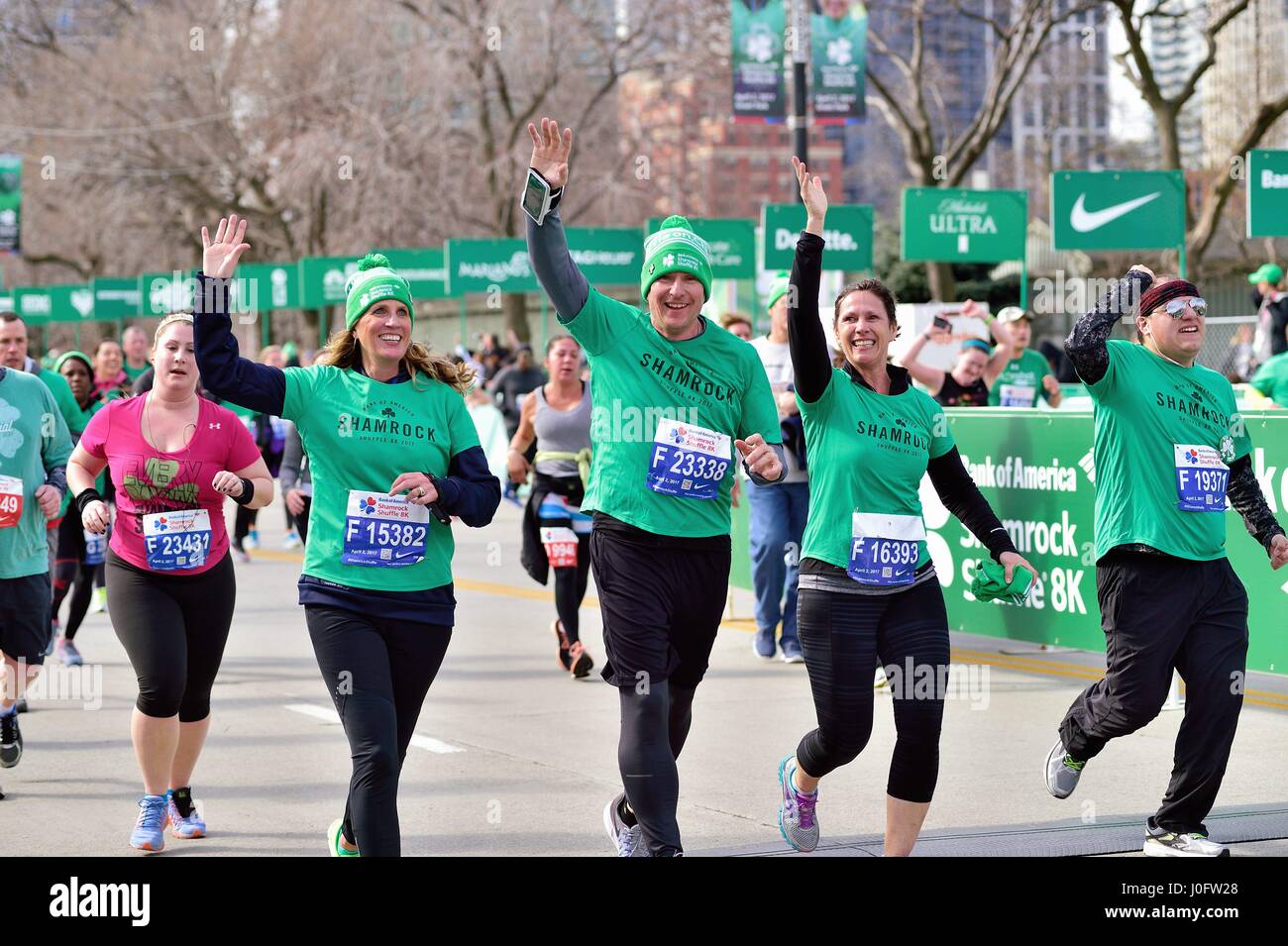 Felice cluster di corridori che attraversa la linea di arrivo al 2017 Shamrock Shuffle gara a Chicago, Illinois, Stati Uniti d'America. Foto Stock