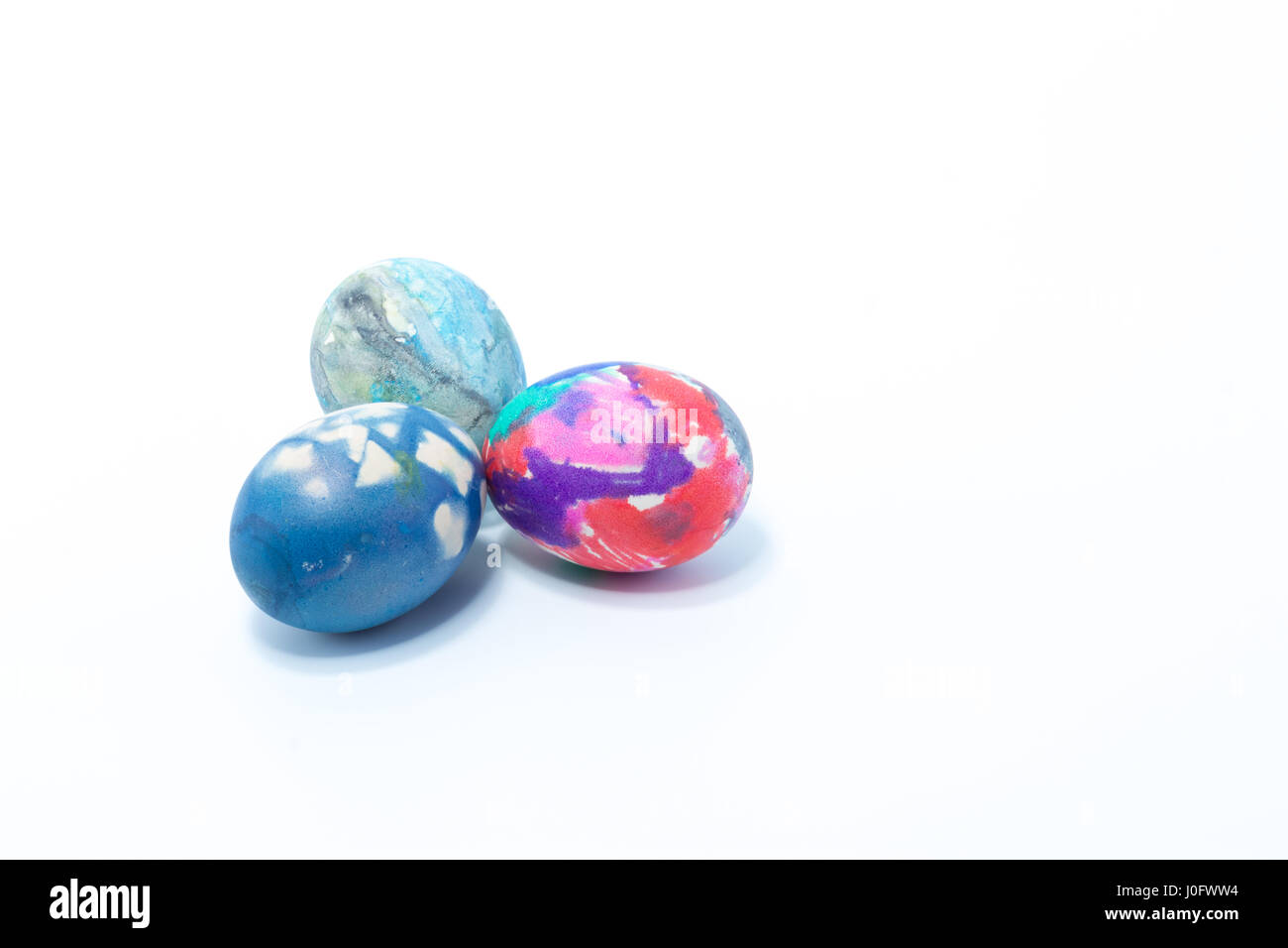 Tre uova pasquali dipinte a mano in home - abstract colori blu scuro, rosa, rosa, bianco e viola - isolato in uno sfondo bianco Foto Stock