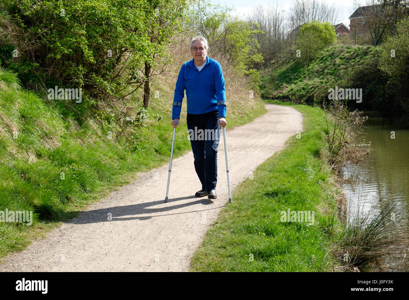 Senior uomo a camminare con le stampelle Foto Stock