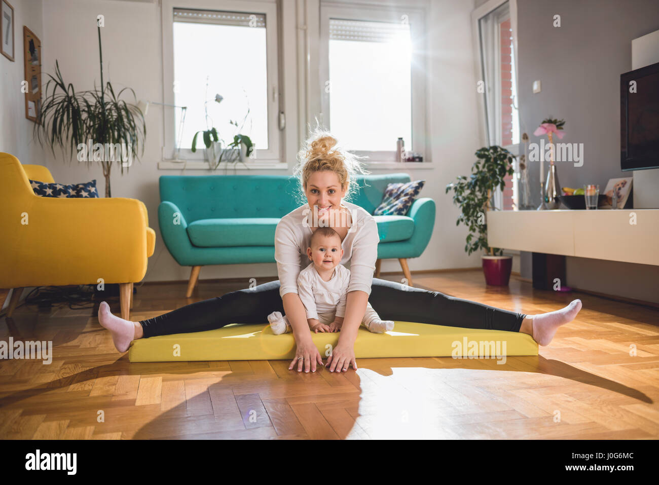 Esercizio di madre con il suo bambino sul tappeto giallo a casa Foto Stock