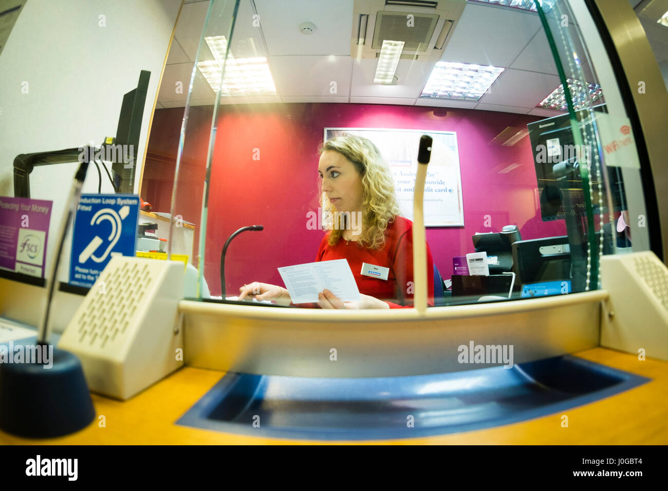 Servizi finanziari: una giovane donna bank teller lavorare dietro il bancone presso una filiale della Nationwide Building Society, REGNO UNITO Foto Stock