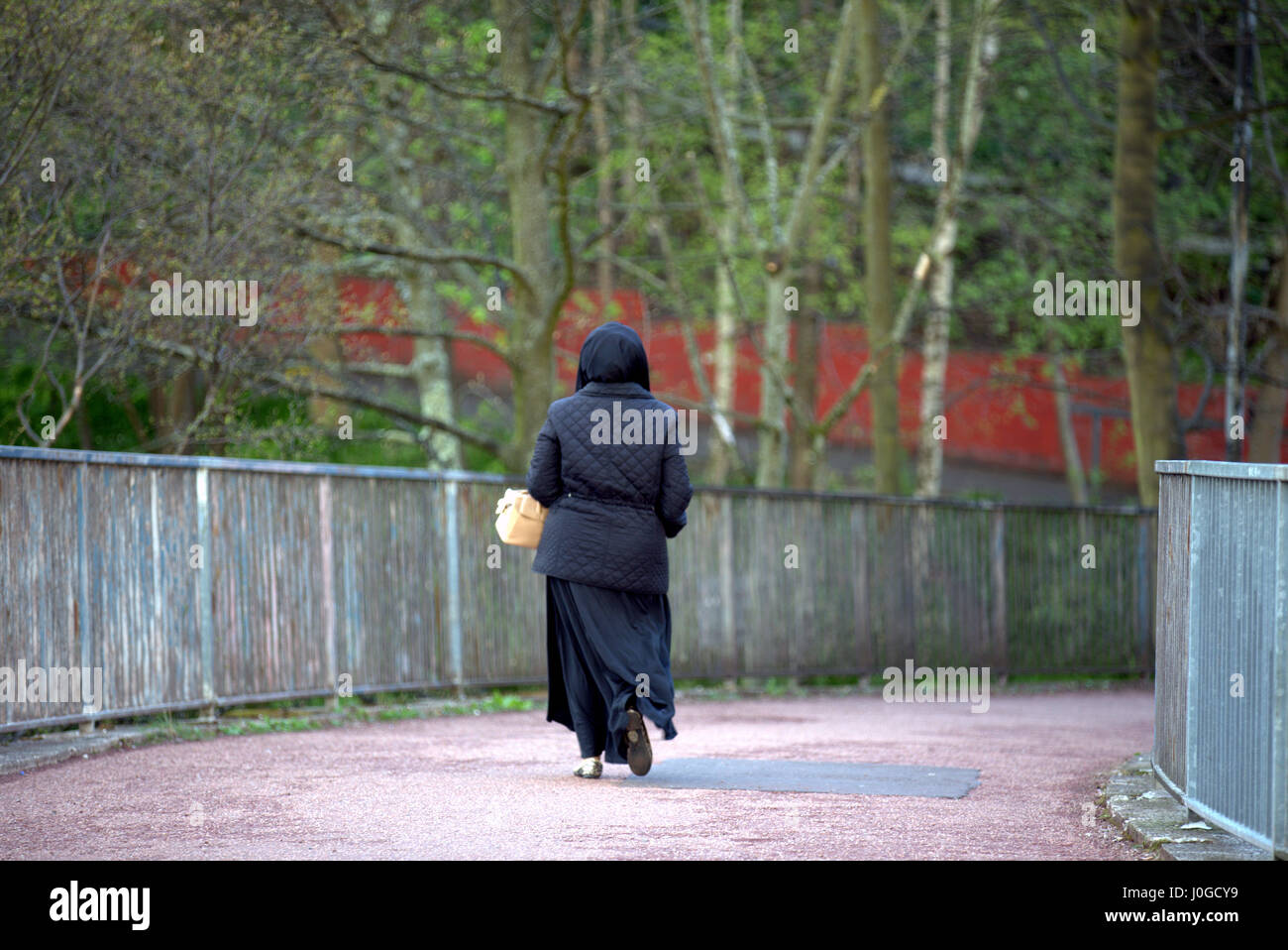 Giovane donna musulmana che indossa il hijab sciarpa camminare da solo nella città Foto Stock