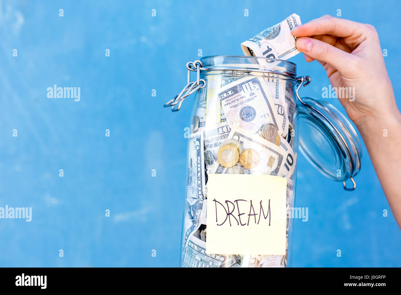 Tenendo una bottiglia piena di risparmio di denaro per sogno Foto Stock