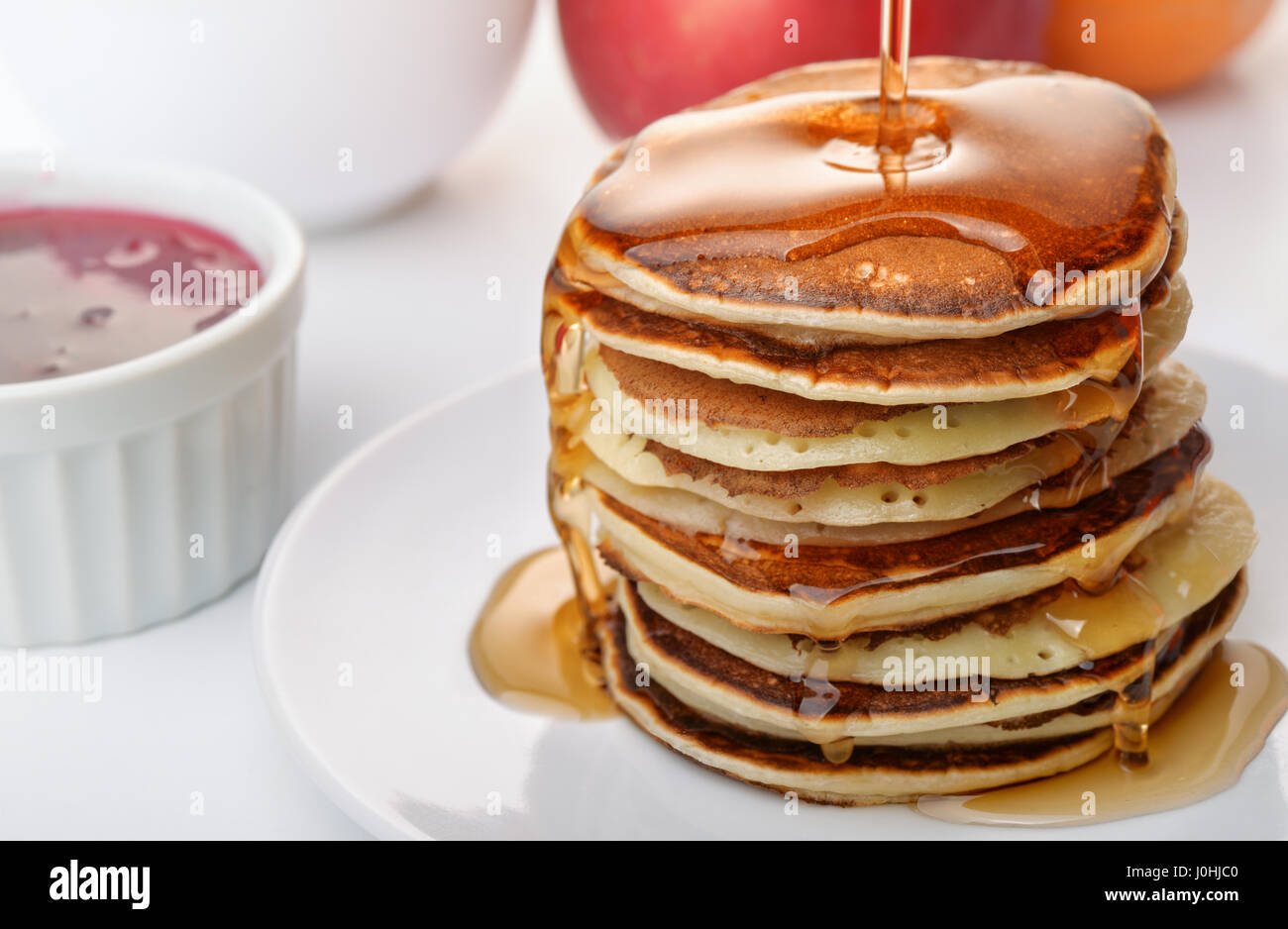 Stii vita con stack frittelle versando lo sciroppo marple Foto Stock