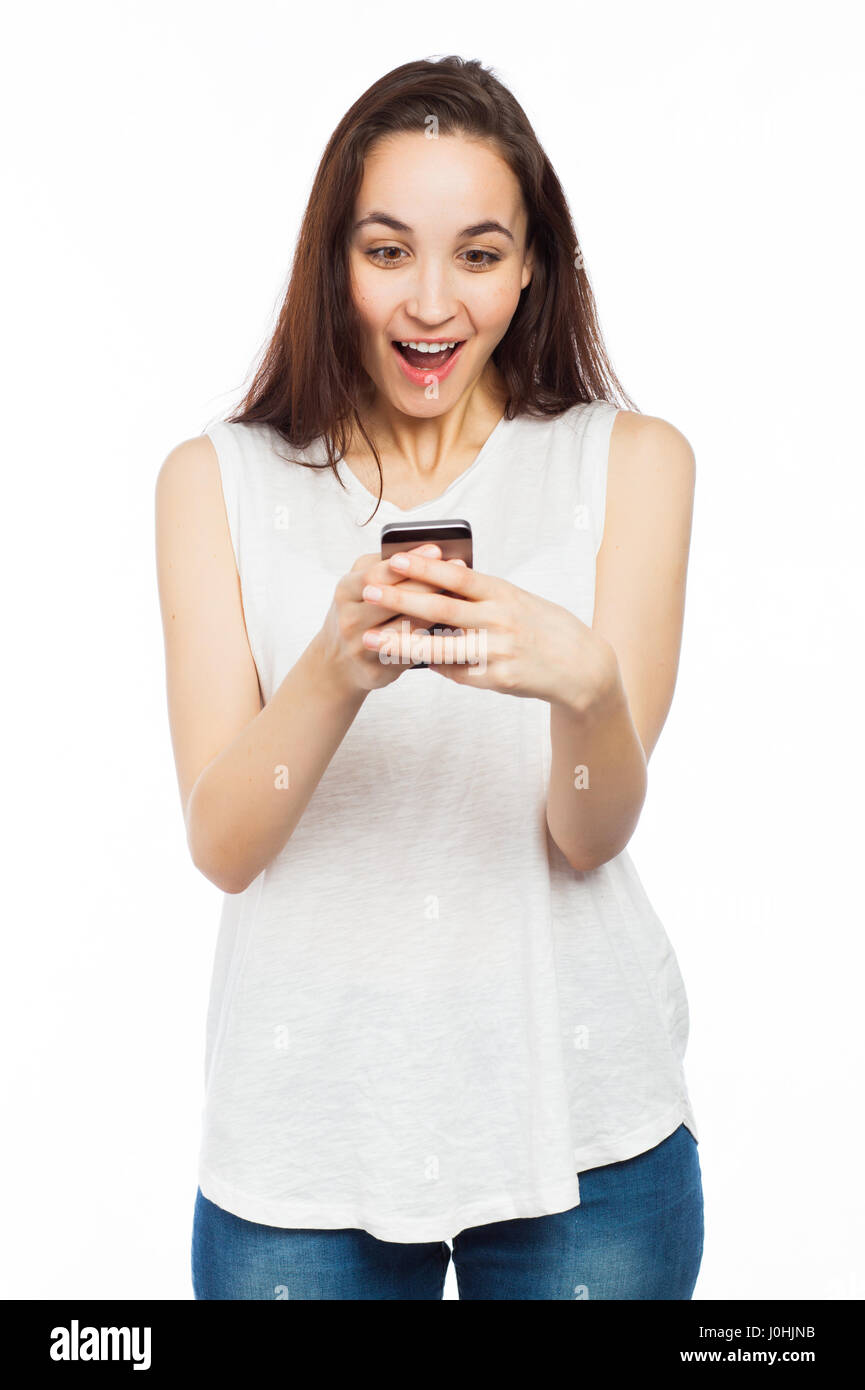 Giovane donna guardando sorpreso utilizzando il suo telefono, isolato su bianco Foto Stock
