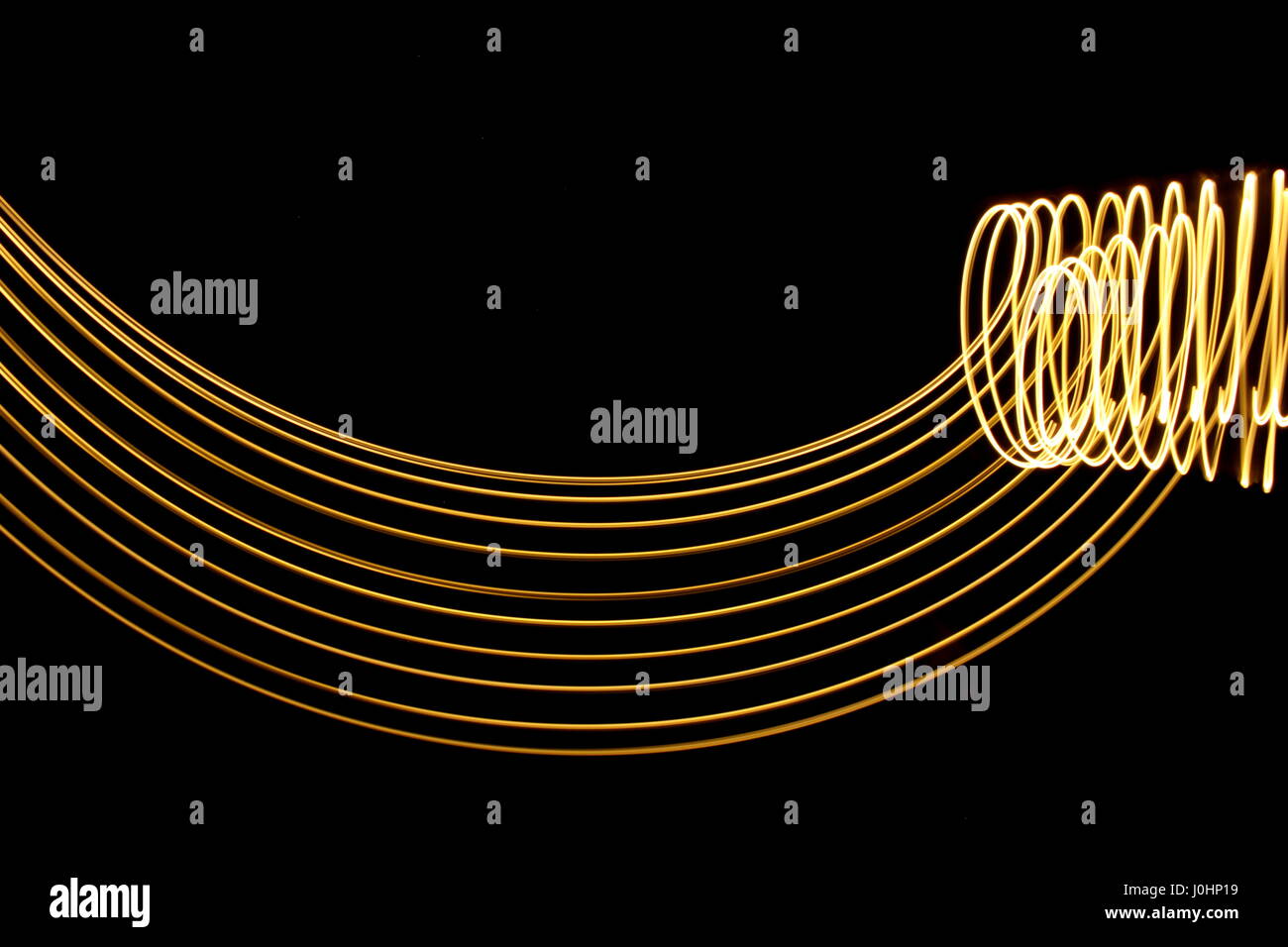Luce fotografia pittura su uno sfondo nero. Neon astratta volute di metallico in color giallo oro, fotografie con lunghi tempi di esposizione. Foto Stock