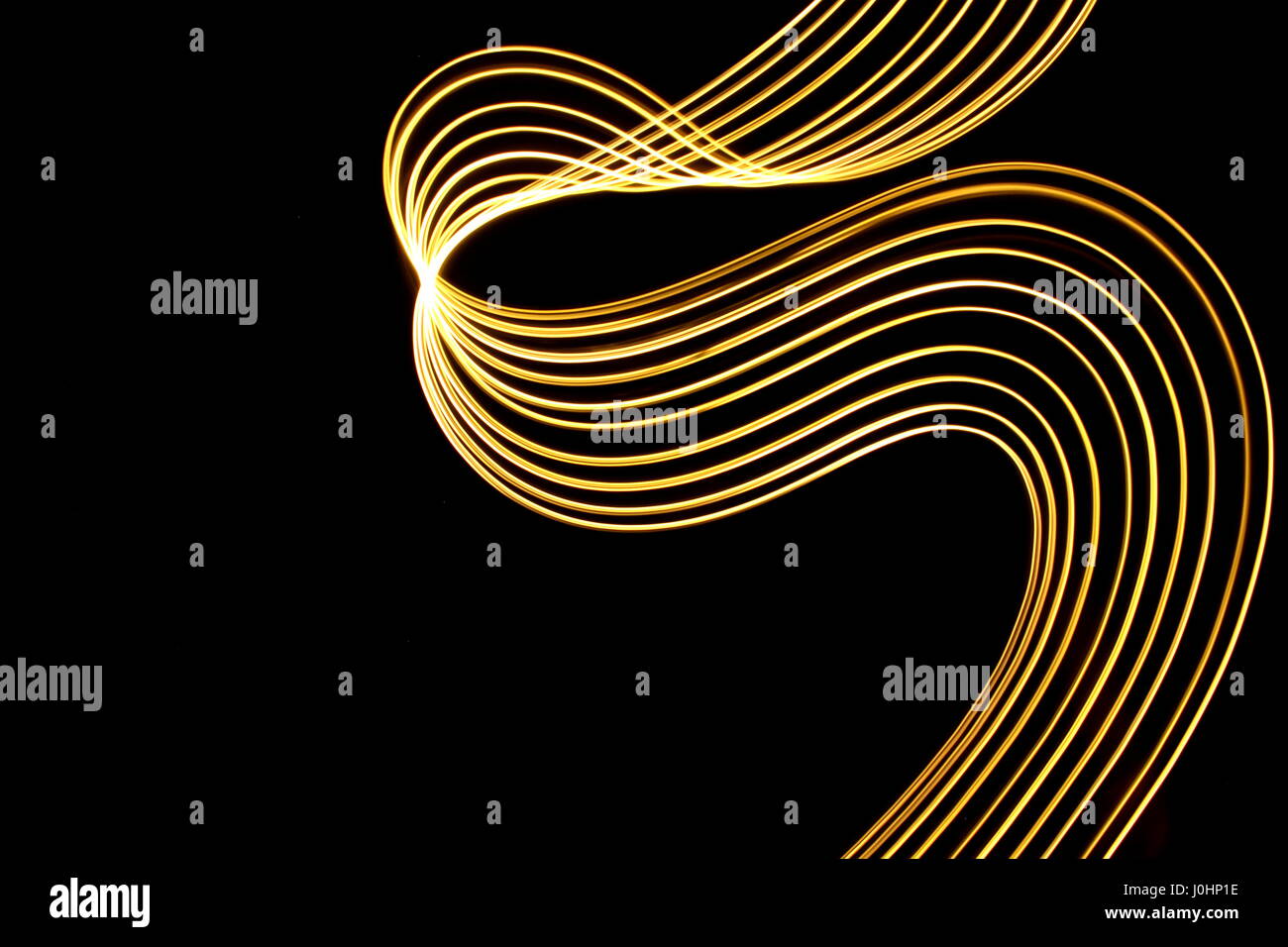 Luce fotografia pittura su uno sfondo nero. Neon astratta volute di metallico in color giallo oro, fotografie con lunghi tempi di esposizione. Foto Stock