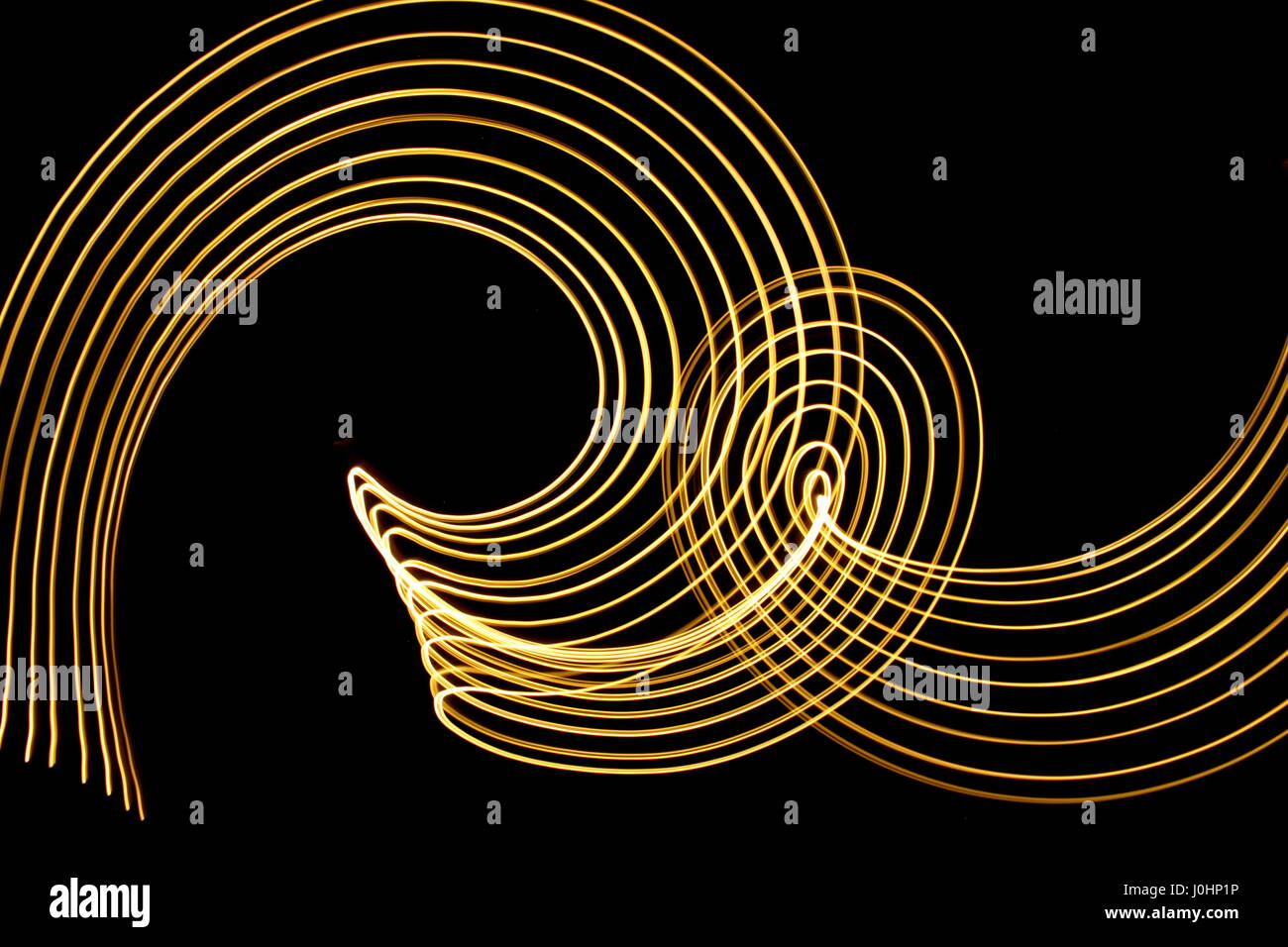 Luce fotografia pittura su uno sfondo nero. Neon astratta volute di metallico in color giallo oro, fotografie con lunghi tempi di esposizione. Foto Stock