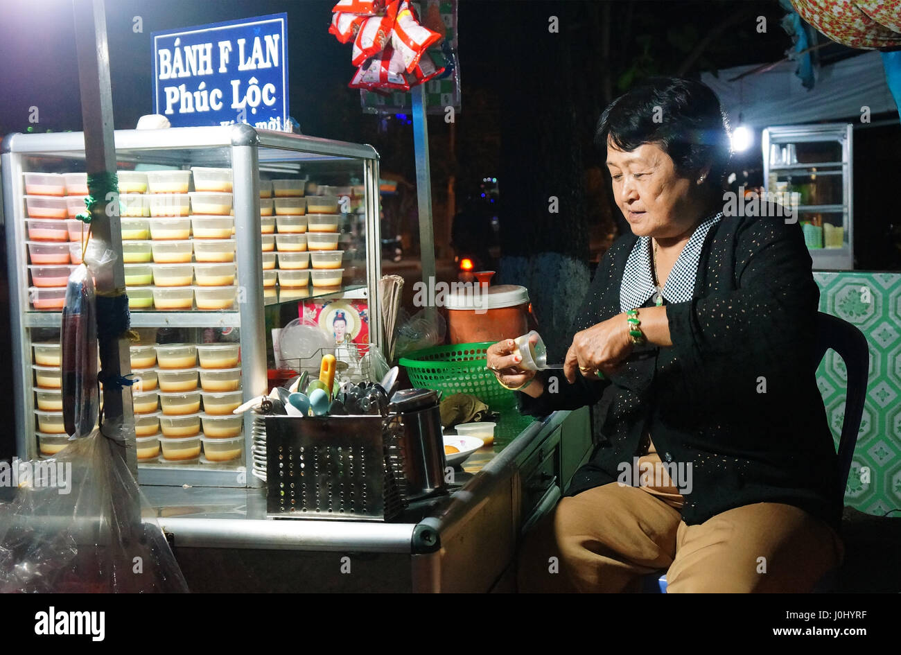 Ho Chi Minh city, Viet Nam, Asia pavimentazione cake shop, Vietnamita donna vendere creme caramel ( flan cake), dolce gustoso cibo durante la notte, Vietnam Foto Stock