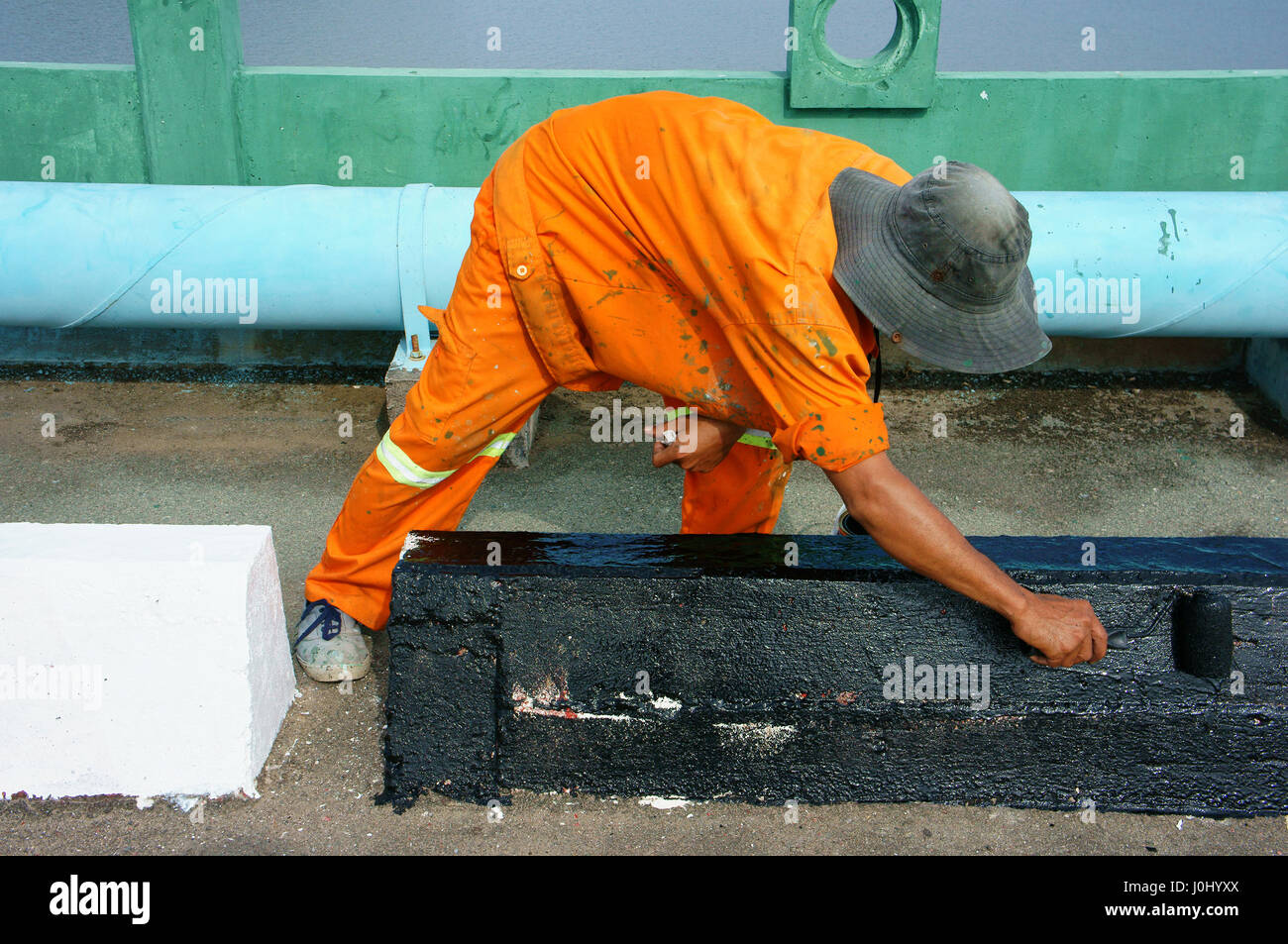 Lavoratore asiatico lavorando su street, Vietnamita uomo pittura vernice per il traffico su strada asfaltata, usura maschio arancione di usura di lavoro, Ho Chi Minh City, Vietnam Foto Stock