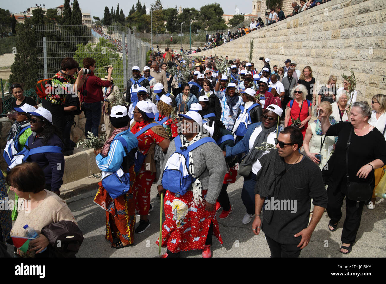 Nero pellegrini cristiani inizia a piedi verso il basso da Mount Olive in una Domenica delle Palme processione portando Ulivi e Palme rami, alcune cantate e alcuni pregare. Foto Stock