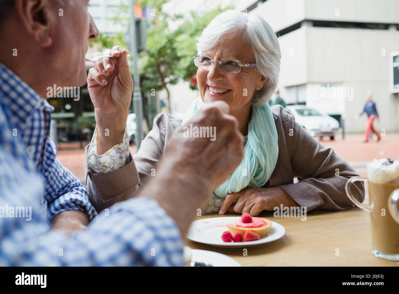 Senior donna dolce alimentazione cibo per l'uomo in outdoor cafÃƒÂ© Foto Stock