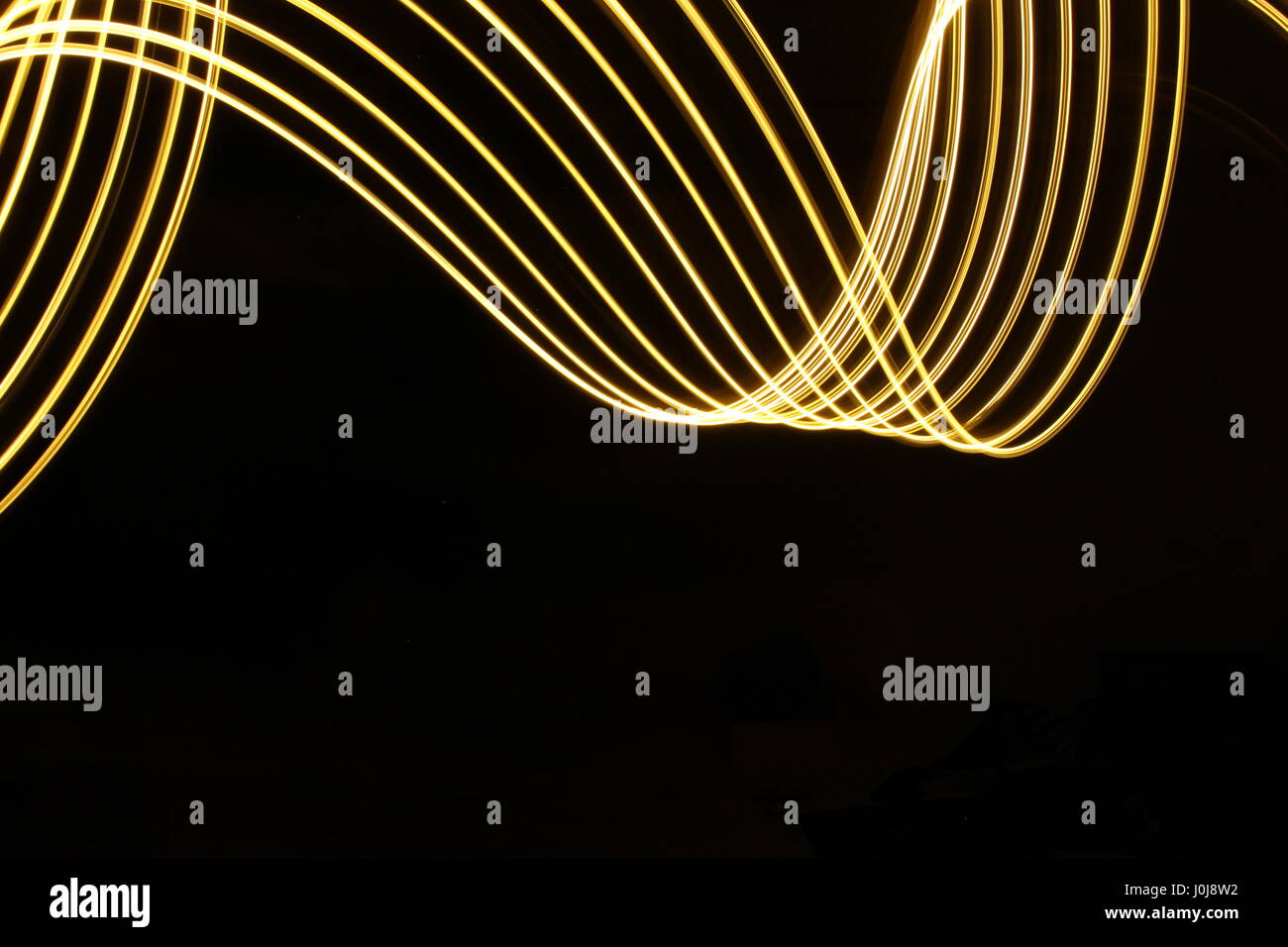 Gold light loop di pittura e disegno di turbolenza, su uno sfondo nero. Fotografie con lunghi tempi di esposizione, la vibrante neon color oro, in un astratto modello di turbolenza Foto Stock