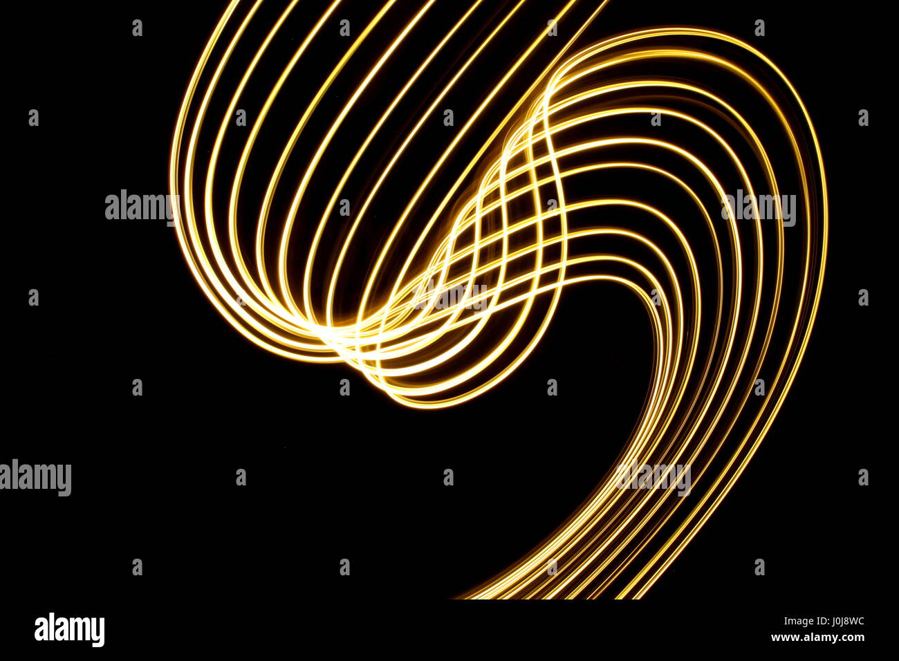 Gold light loop di pittura e disegno di turbolenza, su uno sfondo nero. Fotografie con lunghi tempi di esposizione, la vibrante neon color oro, in un astratto modello di turbolenza Foto Stock