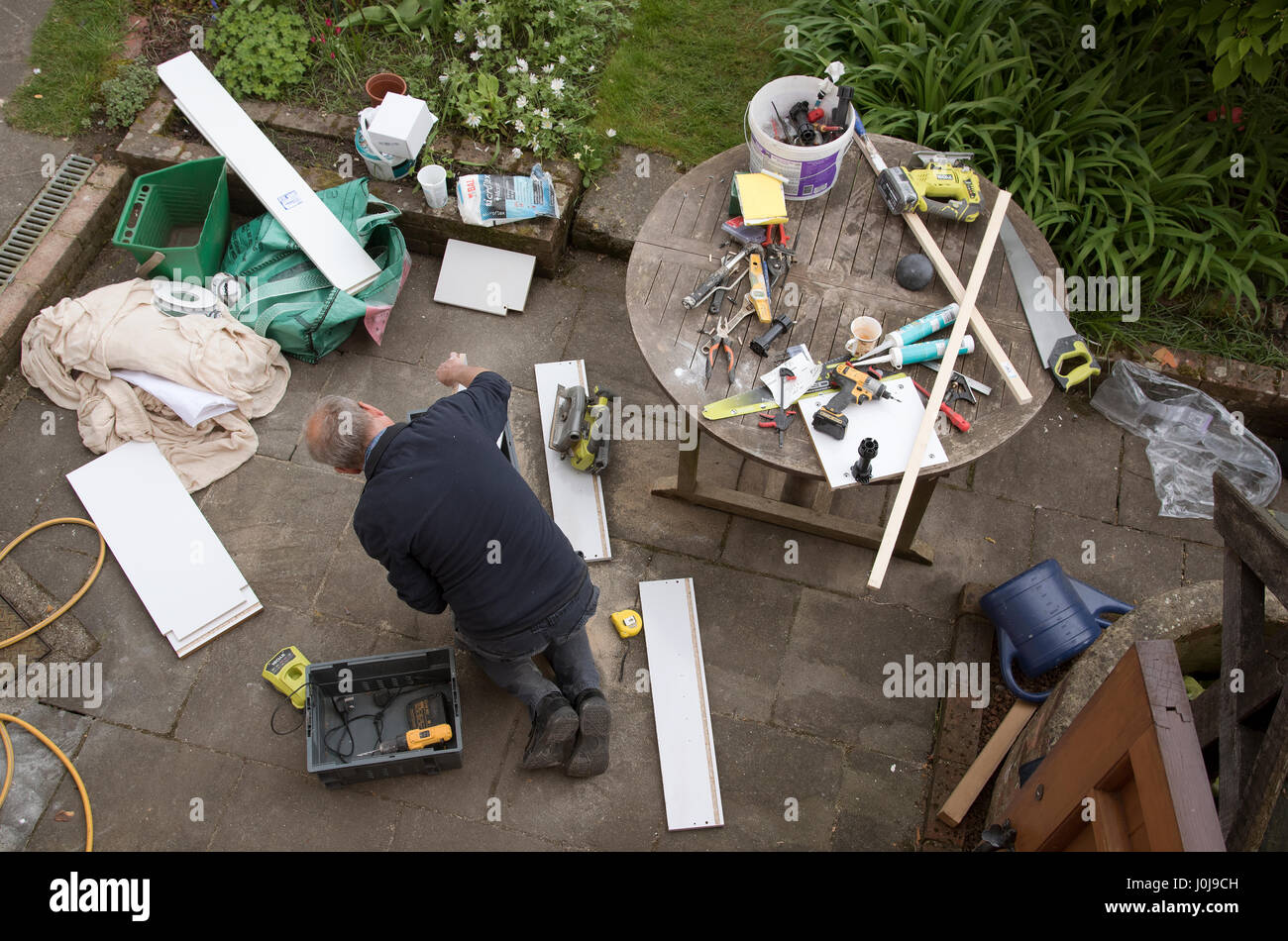 Una panoramica di un tuttofare impegnato in alcuni lavori di DIY su un giardino patio Foto Stock