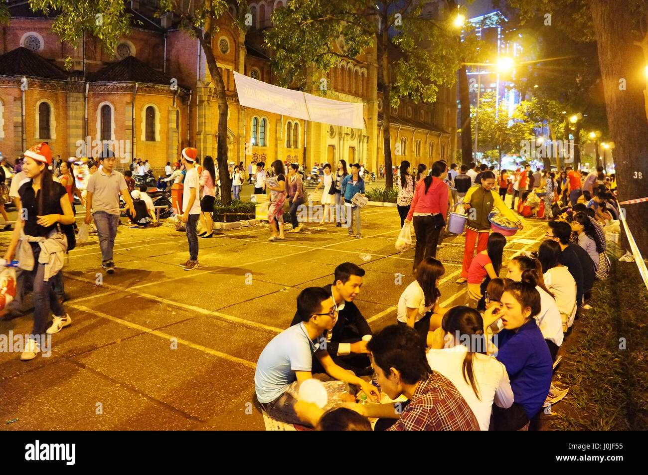 HO CHI MINH CITY, VIET NAM, affollato di atmosfera a Duc Ba Cattedrale di notte di Natale, lampada gialla, giovani sedersi e godersi lo stile di vita della gioventù, Vietnam Foto Stock