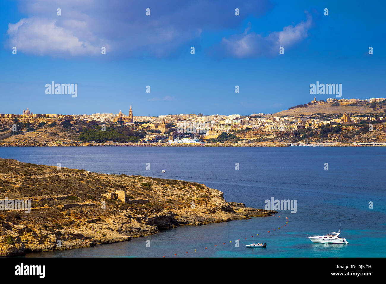 A Comino e Malta - Motoscafo e yacht alla famosa laguna blu e sulle isole di Comino e Gozo e Mgarr città in background su un luminoso somma Foto Stock