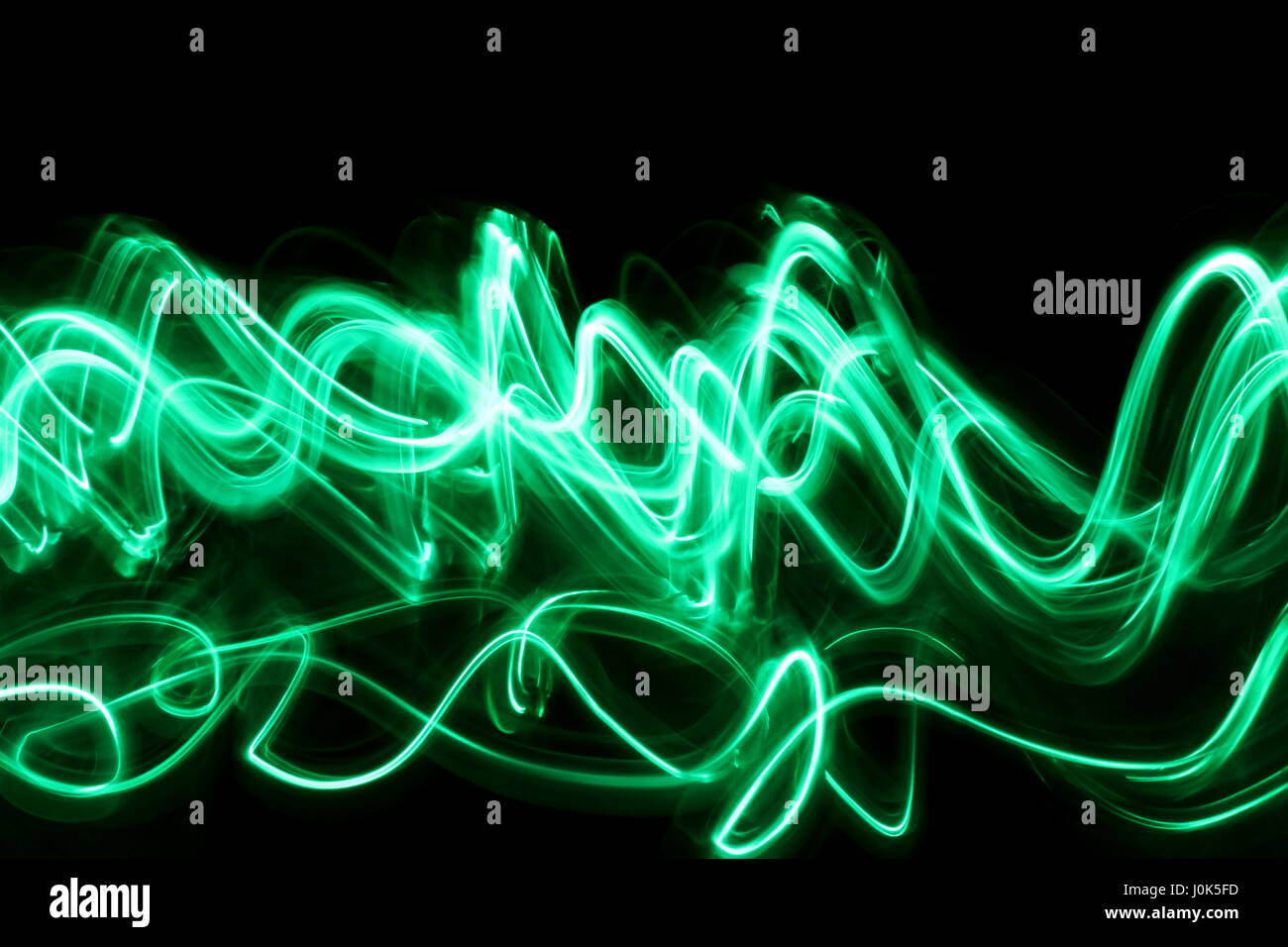 Una lunga esposizione fotografia di neon di colore verde in una configurazione astratta contro uno sfondo nero. Luce fotografia pittura, di colore in astratto Foto Stock