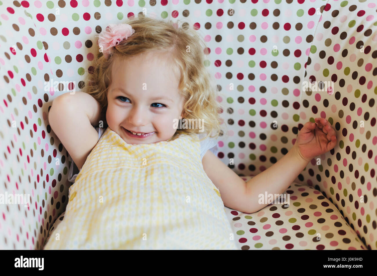 Bimba bionda sorridente in una Polka Dot sedia Foto Stock