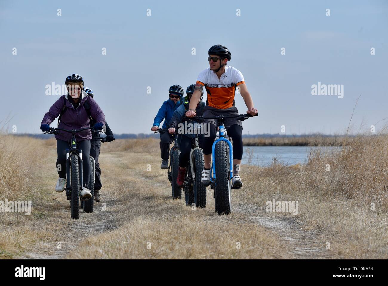 Gruppo di equitazione ecotourists fat tire biciclette attraverso la prairie con la gru di fiducia al di fuori della proprietà Grand Island, Nebraska, Stati Uniti d'America. Foto Stock