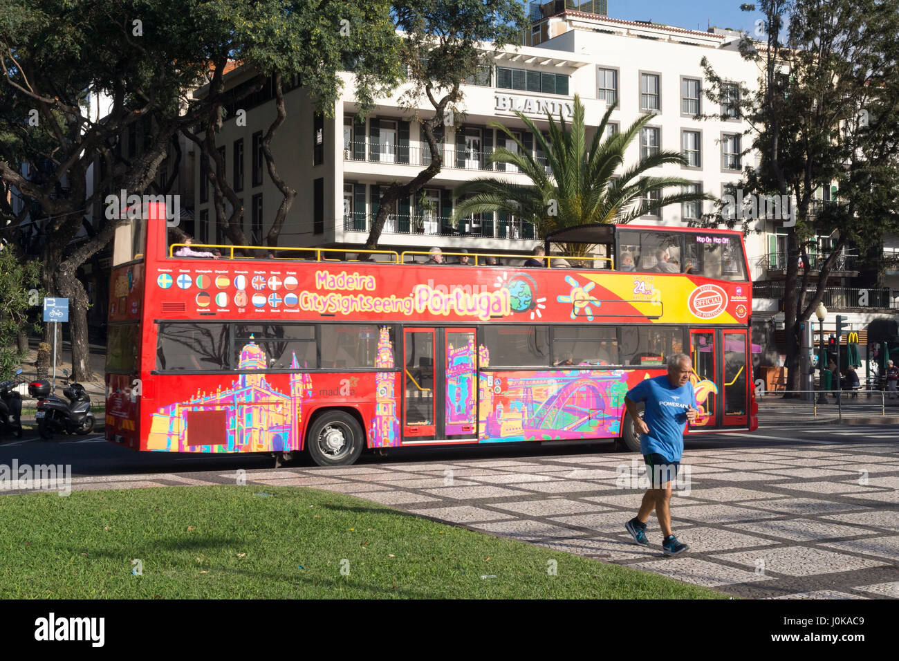 Un locali di Madera uomo jogging al mattino nella parte anteriore di una guida turistica in autobus Funchal Foto Stock