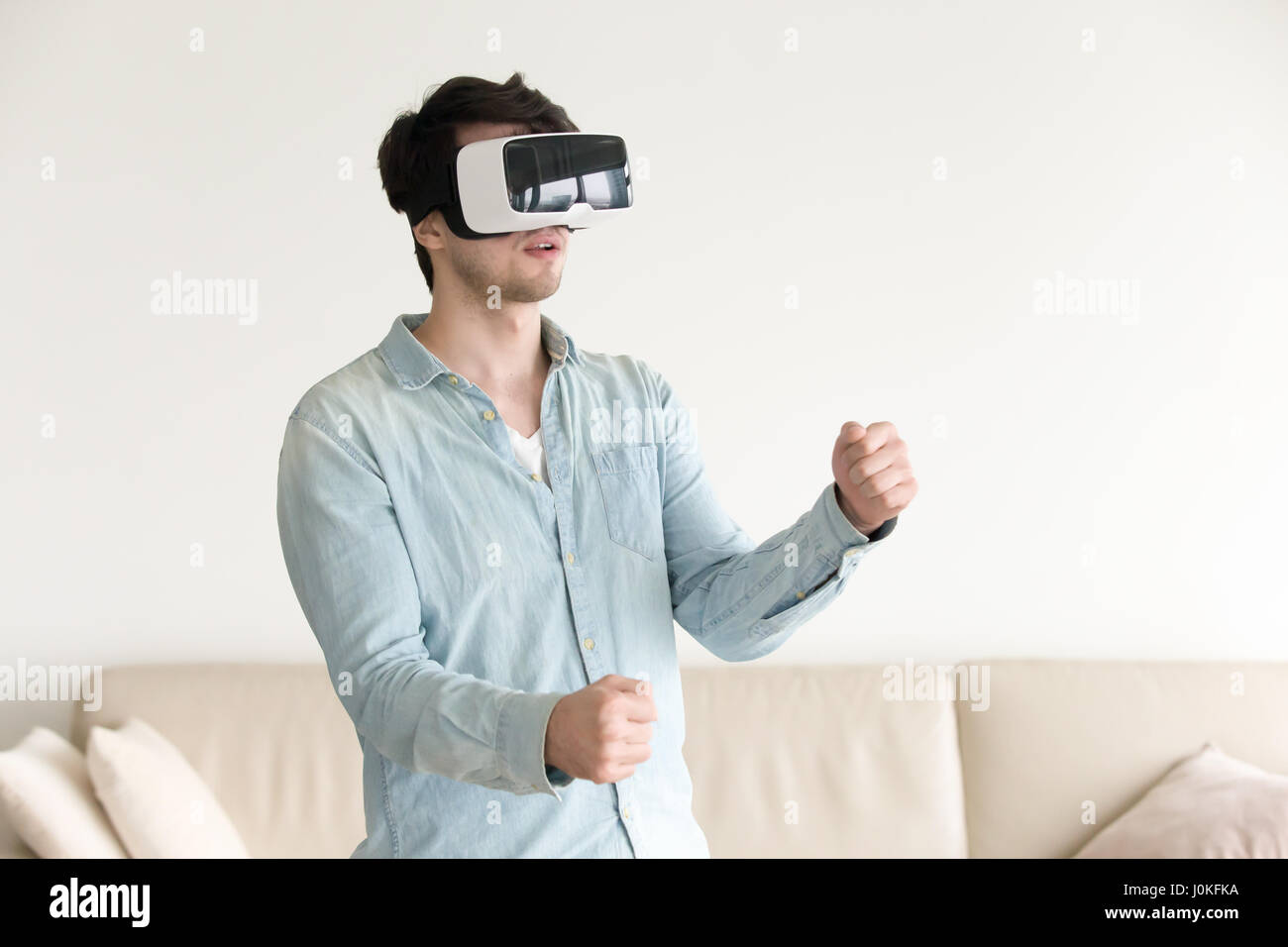 Giocatore maschio indossando occhiali VR, riproduzione di realtà virtuale ga mobile Foto Stock