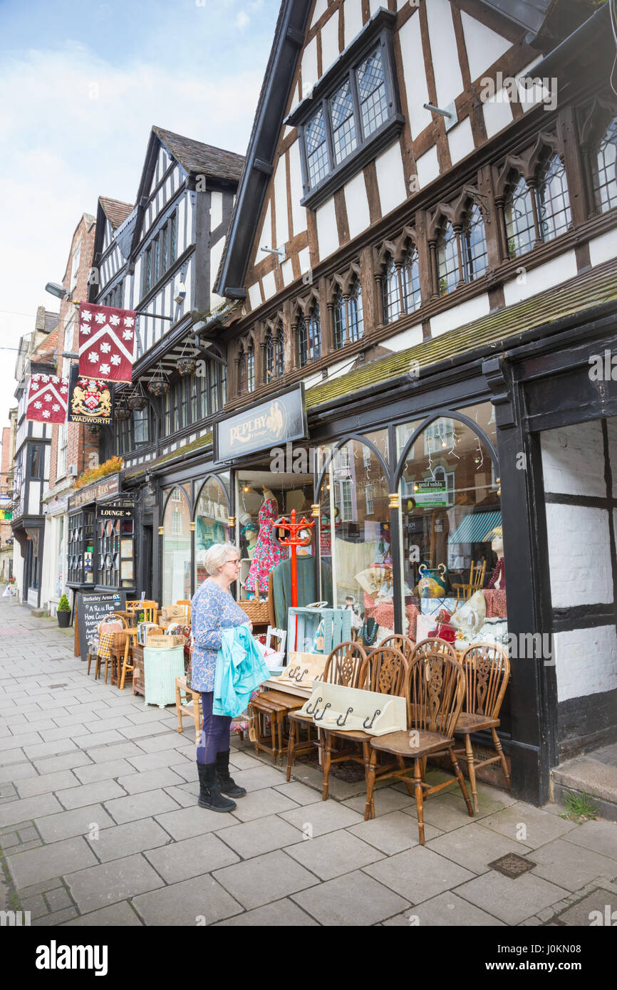 Donna in piedi al di fuori di un negozio nel centro di Tewkesbury, GLOUCESTERSHIRE REGNO UNITO mostra in legno tradizionali edifici incorniciate Foto Stock