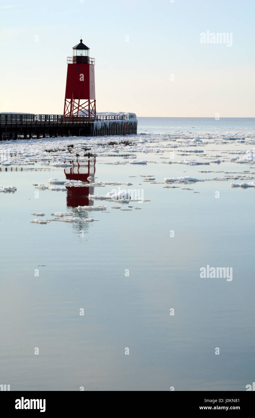 Colpo verticale di un faro rosso riflettente nel ghiaccio acqua punteggiata di lago Michigan su una tranquilla giornata invernale. Foto Stock