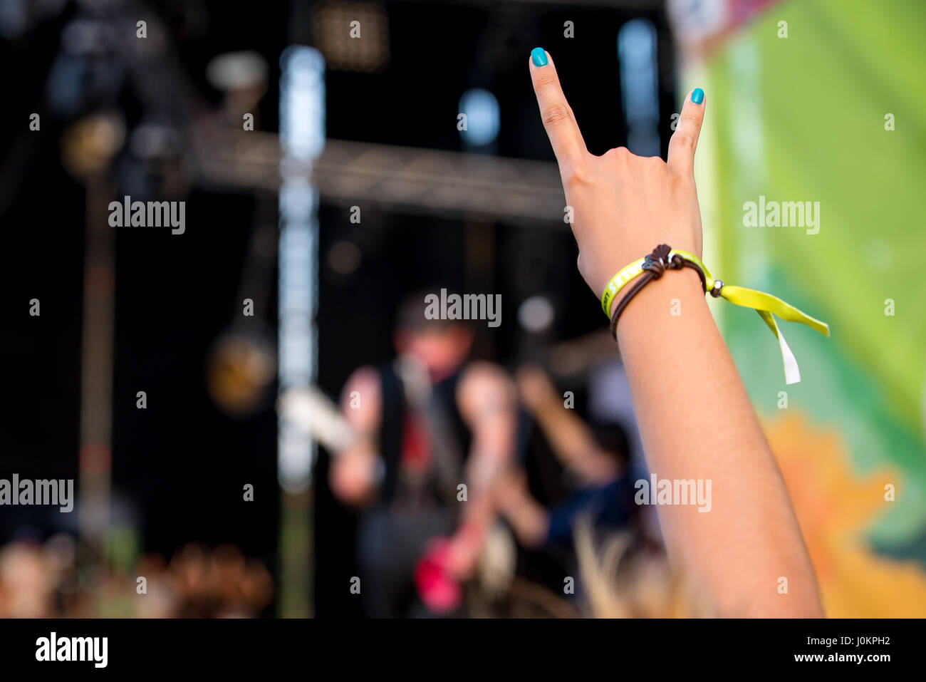 Vista del braccio di un uomo che fa il gesto di corna in un concerto Foto Stock