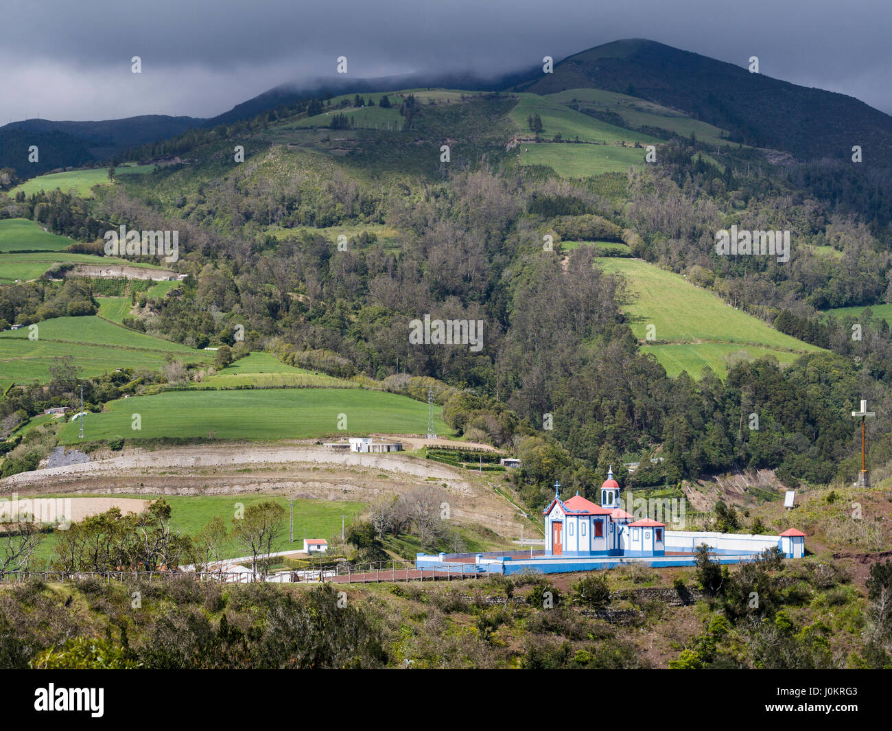 Nossa Senhora do Monte cappella. Situato in alto sopra la città questa piccola cappella brilla al sole come una tempesta travolge le colline dietro. Foto Stock