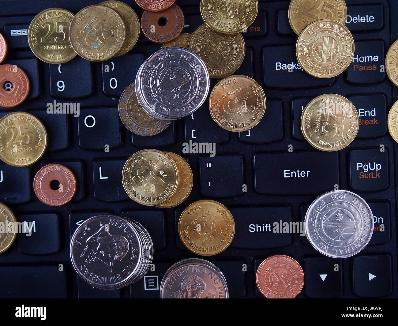 Mazzetto di Philippine peso monete sulla parte superiore di una tastiera di un computer portatile Foto Stock