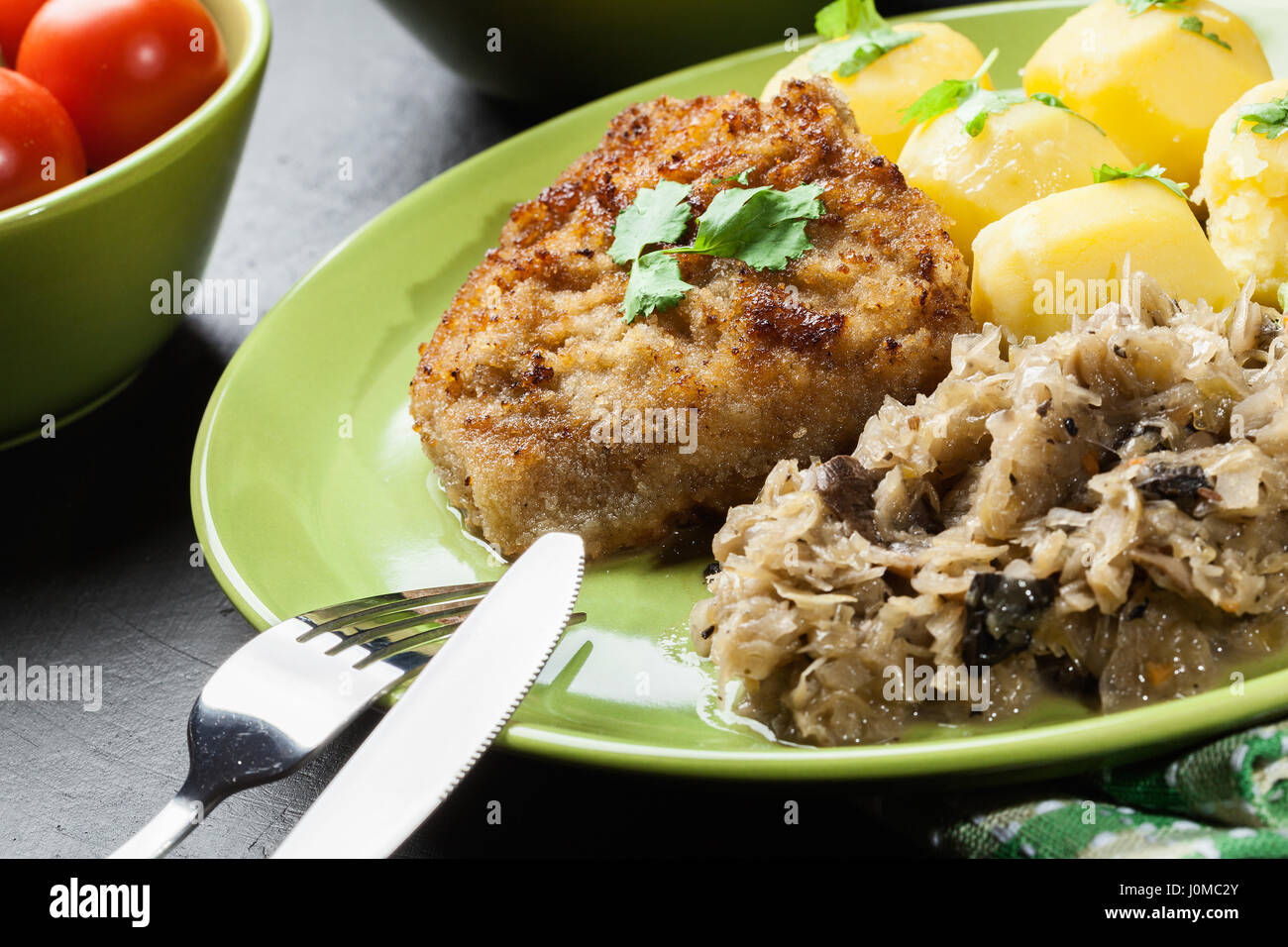 Fritte cotoletta di maiale servito con patate lesse e crauti fritto su una piastra Foto Stock