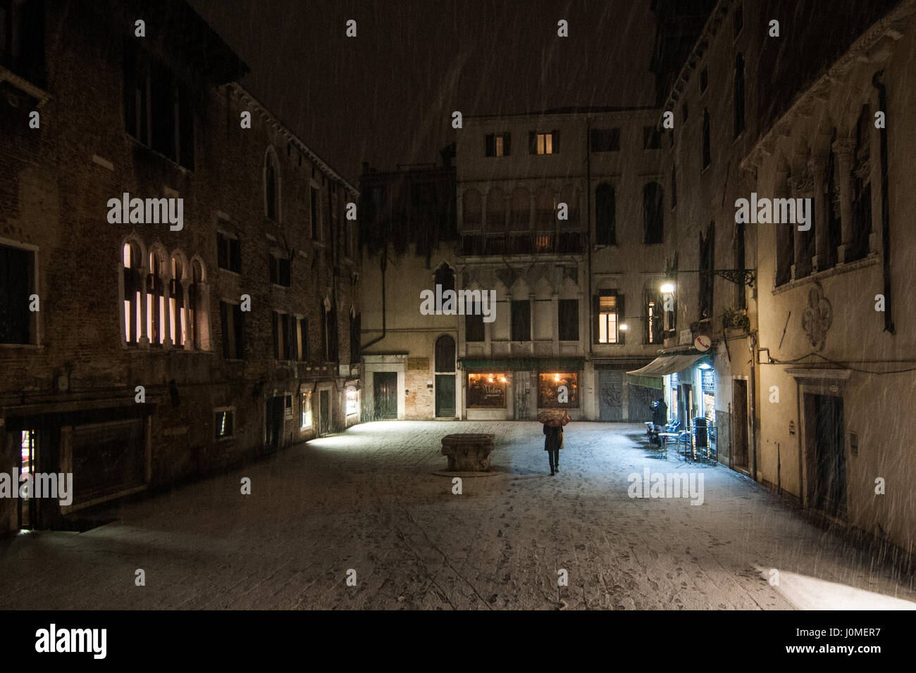 Un uomo cammina in Santa Maria Mater Domini piazza durante una neve pesante a Venezia. Foto Stock