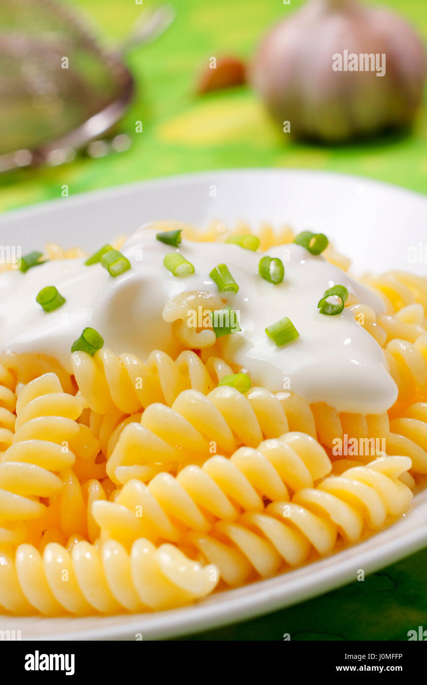 La pasta (fusilli) con crema e d erba cipollina sulla piastra con sfondo non focalizzato Foto Stock