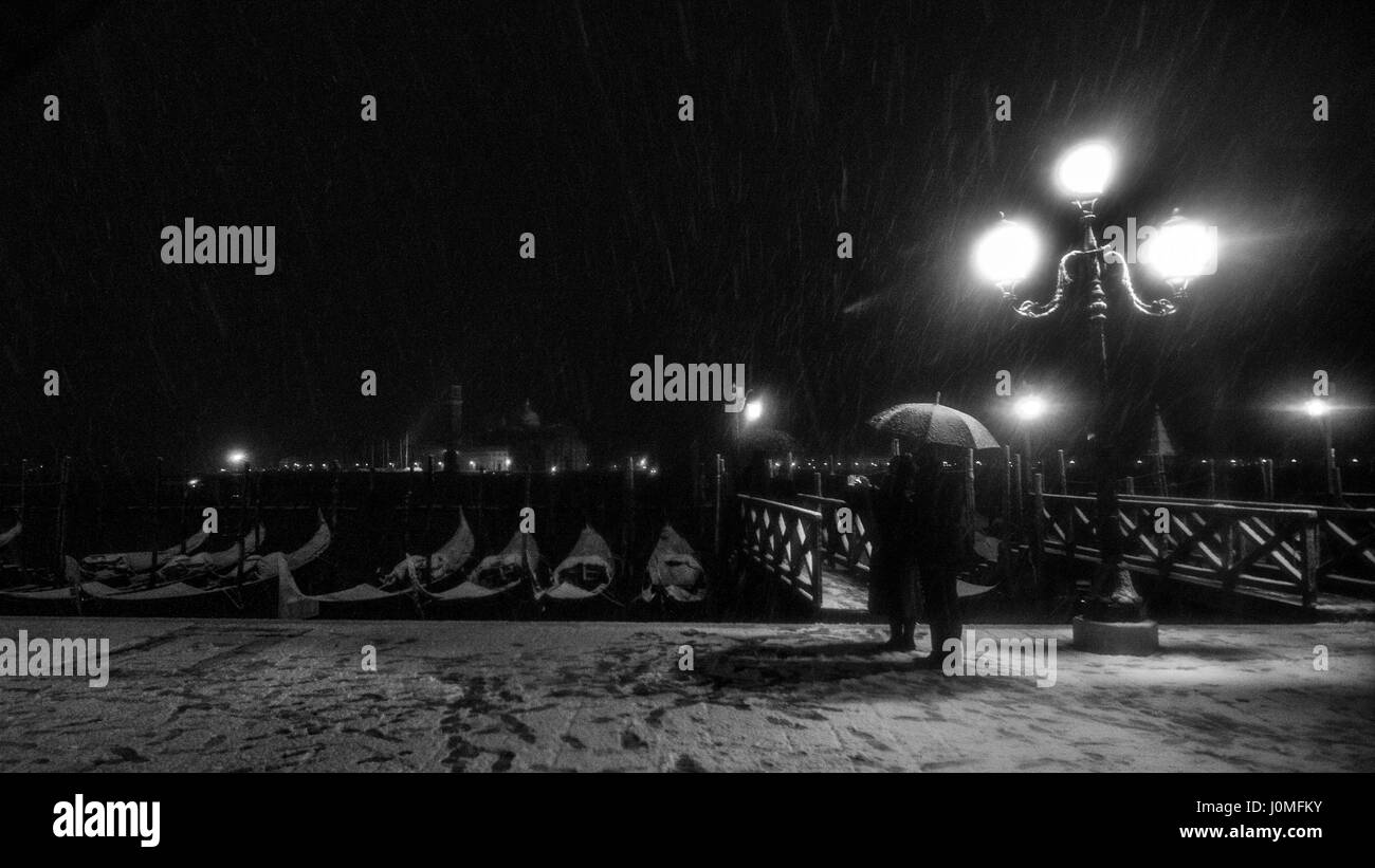La gente cammina accanto a una stazione di Gondole durante un pesante la caduta di neve a Venezia. Foto Stock