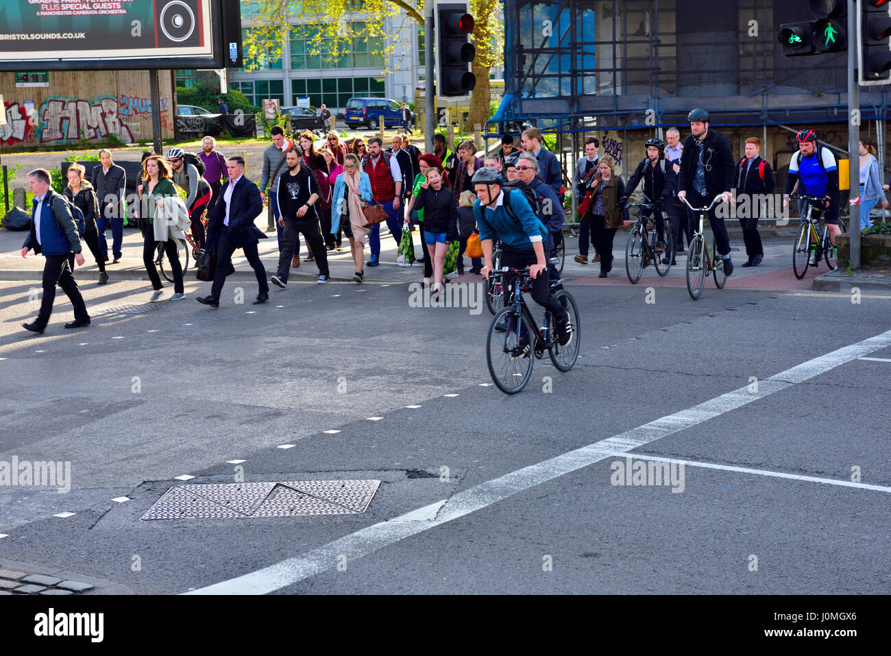 I pedoni e i ciclisti che attraversano la strada in corrispondenza di intersezione con luce verde, Bristol, Inghilterra Foto Stock