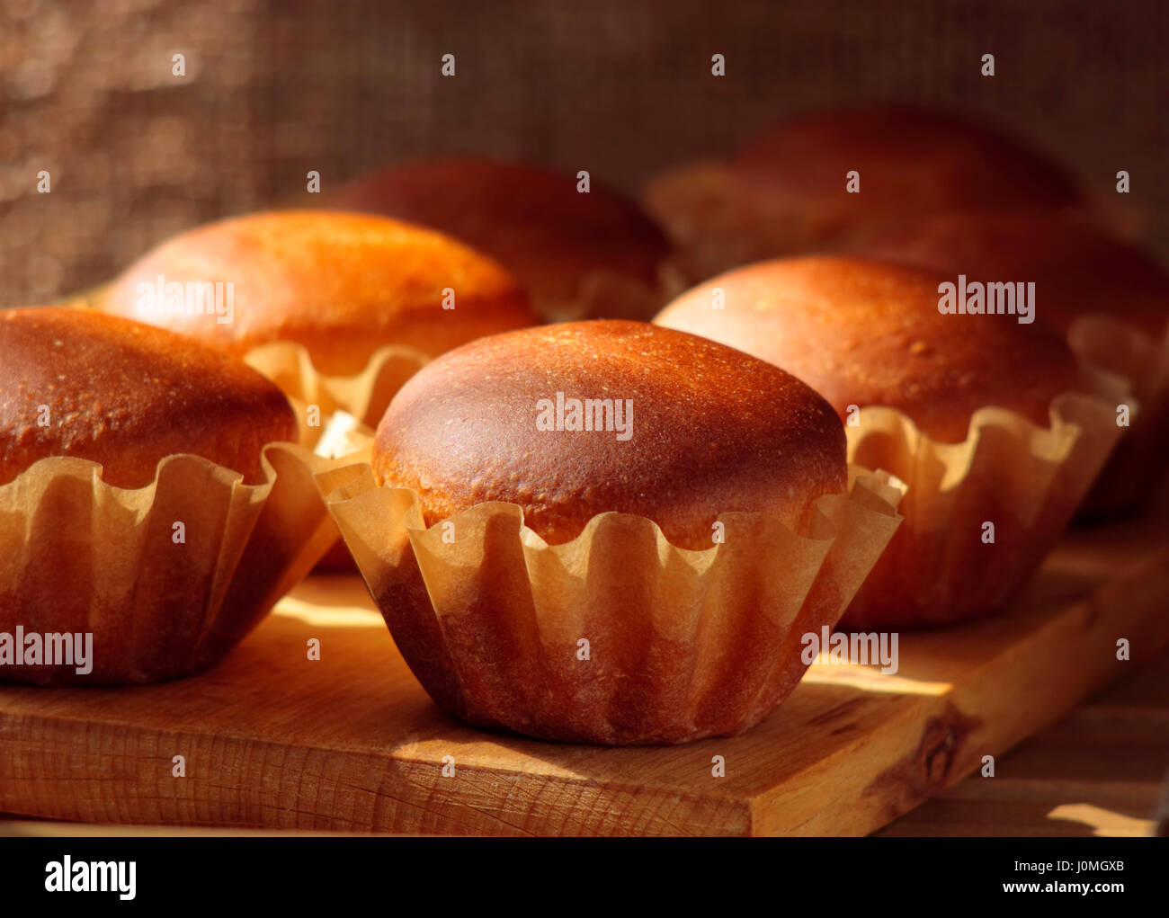 Home muffin fatti in uno stampo di carta teglie su una tavola di legno. Focus sul primo piano di muffin. Foto Stock