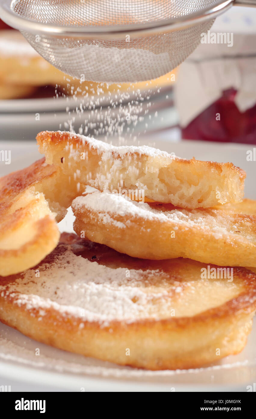 La vista ravvicinata di ciambelle polacca (racuchy) versata con zucchero a velo. Telaio stretto con sfondo fuori fuoco. Foto Stock