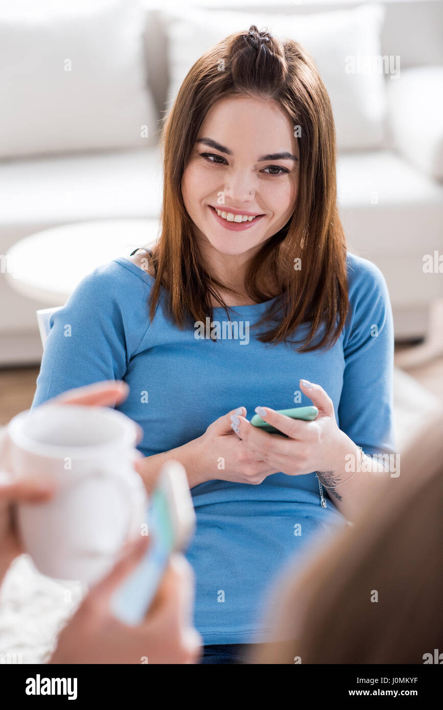 Ritratto di giovane donna attraente tenendo lo smartphone e sorridente Foto Stock